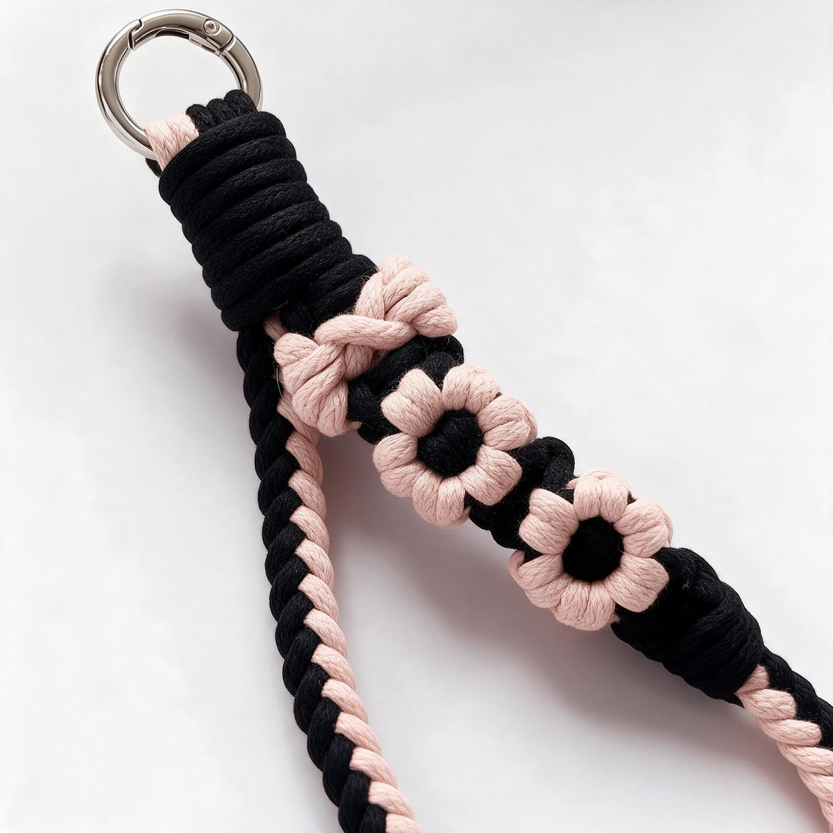 Close-up of artisan black and pink braided cotton flower phone strap with round carabiner clasp - Rove Cord
