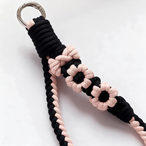 Close-up of artisan black and pink braided cotton flower phone strap with round carabiner clasp - Rove Cord
